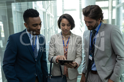 Multi-ethnic business people discussing over digital tablet in office elevator