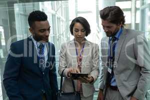 Multi-ethnic business people discussing over digital tablet in office elevator