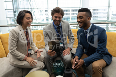 Multi-ethnic business people sitting and discussing over the digital tablet in lobby at office