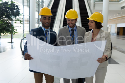 Multi-ethnic business architect discussing over the blue print in lobby at office