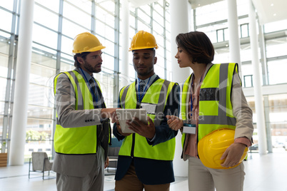 Multi-ethnic business architect discussing over digital tablet at office lobby