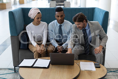 Multi-ethnic business people discussing over laptop in the lobby