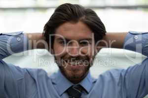 Young Caucasian businessman relaxing with hands behind head in modern office