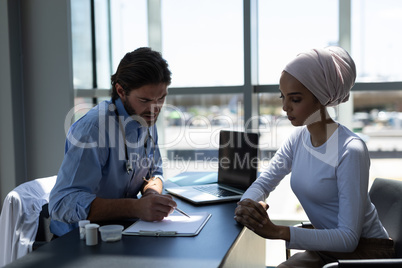 Disabled mixed-race woman and Caucasian male doctor interacting with each other