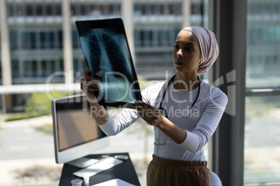 Beautiful mixed-race female doctor looking at x-ray report in hospital