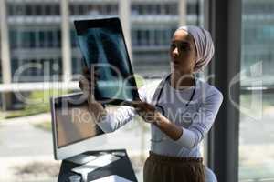 Beautiful mixed-race female doctor looking at x-ray report in hospital