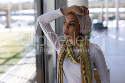 Young mixed-race female executive looking through window in modern office