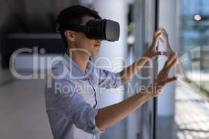 Asian male executive using virtual reality headset in modern office