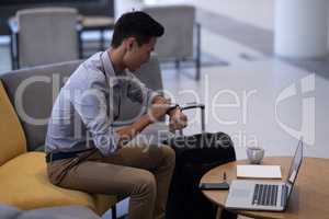 Asan male executive using smartwatch in modern office