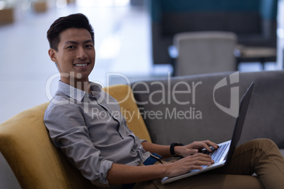 Male executive using laptop in the lobby at office