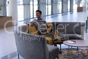 Asian male executive having coffee while using laptop in the lobby
