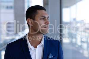 Young mixed-race businessman looking away in modern office