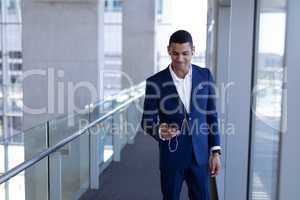 Young mixed-race businessman listening music on mobile phone in modern office