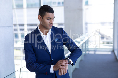 Young mixed-race businessman using smartwatch in modern office