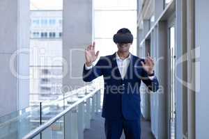 Young mixed-race businessman using virtual reality headset in modern office