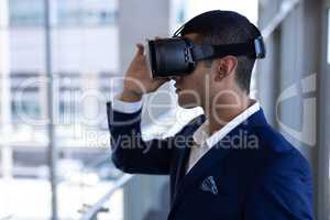 Mixed-race businessman using virtual reality headset in modern office