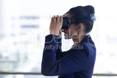 Young mixed-race businesswoman using virtual reality headset in modern office