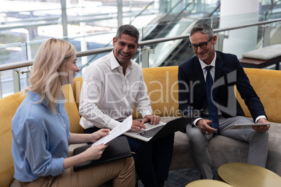 Caucasians business executives interacting with each other on sofa in office