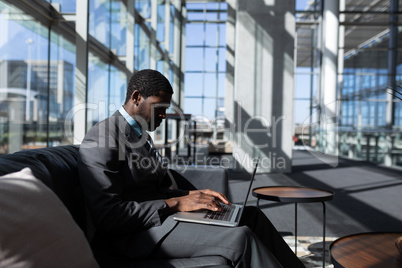 African-American businessman sitting on the sofa and using laptop in modern office