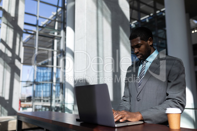 African-American businessman with coffee cup using laptop in office