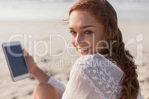 Young Caucasian woman using digital tablet on the beach