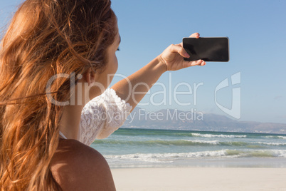 Young woman taking selfie with her mobile phone on the beach