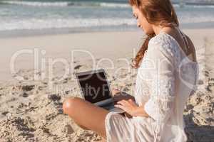 Young Caucasian woman using laptop on the beach