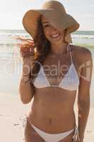 Young Caucasian woman in hat and bikini looking at camera