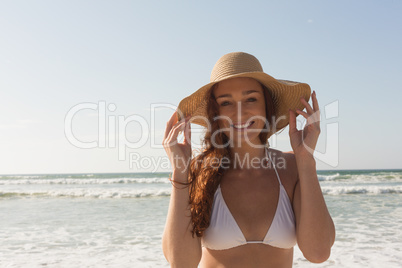 Young Caucasian woman in hat and bikini on the beach