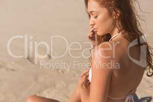 Young Caucasian woman in bikini sitting on the beach