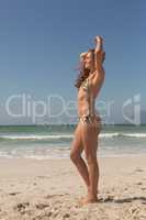 Side view of beautiful young Caucasian woman in bikini looking away on the beach