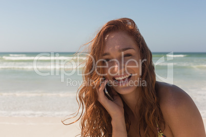 Young woman in bikini talking to her mobile phone at beach