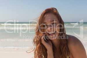 Young woman in bikini talking to her mobile phone at beach