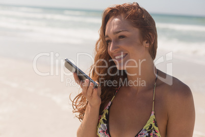 Young woman in bikini talking to her mobile phone at beach