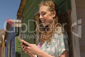 Young Caucasian woman using mobile phone at beach hut