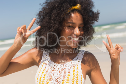 Young African American woman showing victory sign on the beach