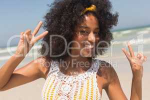 Young African American woman showing victory sign on the beach