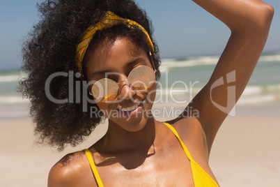 Young African American woman in bikini and sunglasses looking at camera on the beach