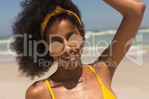 Young African American woman in bikini and sunglasses looking at camera on the beach