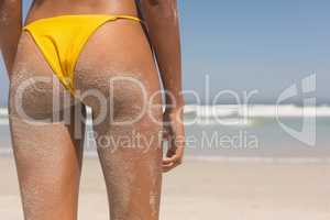 Young African American woman in yellow bikini standing on the beach