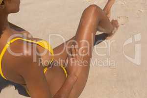 Young African American woman in yellow bikini relaxing on the beach