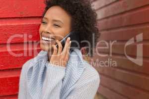 Young African American woman talking to mobile phone at beach hut