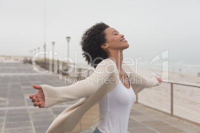 Young African American woman with arms stretched out standing at promenade
