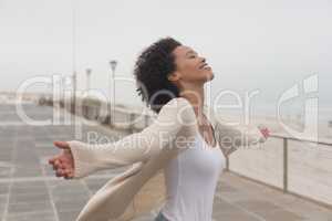 Young African American woman with arms stretched out standing at promenade