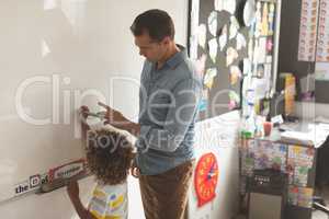 Caucasian teacher teaching something to a mixed-race school boy on a whiteboard