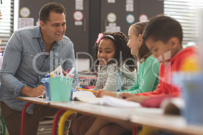 Surface level view of a teacher interacting with school kids while sitting in classroom