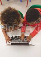 Overhead view of two mixed-race school boys taping on the keyboard of their laptop