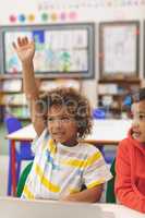Front view of mixed-race schoolboy raising his hand in with his friend next to him