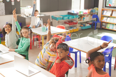 Overhead view of school kids raising hand to answer of teacher question