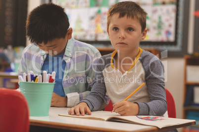 School kids drawing on notebook in classroom